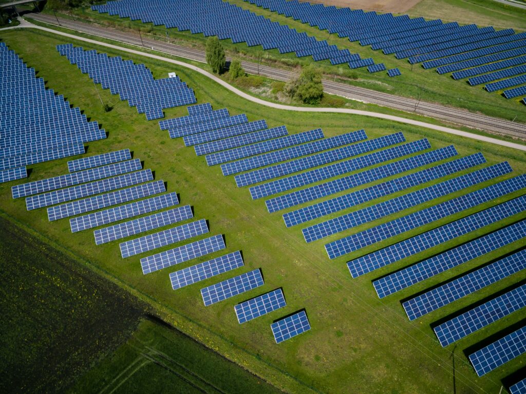 Photovoltaikanlage auf Grünfläche mit Bahntrasse im Hintergrund – Symbol für nachhaltige Energiegewinnung und Flächeneffizienz von PV-Anlagen