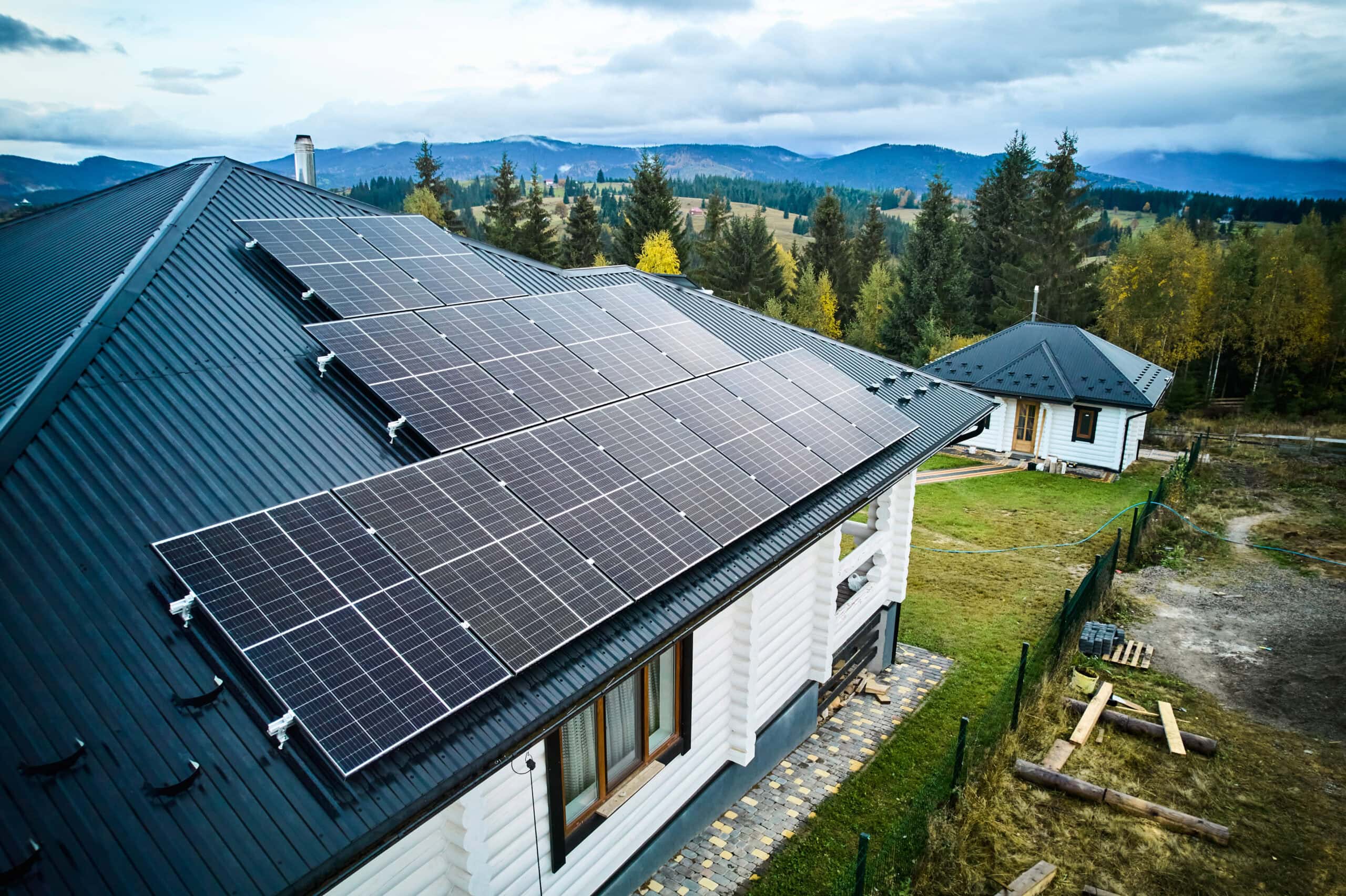 Photovoltaikanlage auf dem Schrägdach eines Einfamilienhauses aus der Vogelperspektive, mit mehreren Solarmodulen und grüner Landschaft im Hintergrund